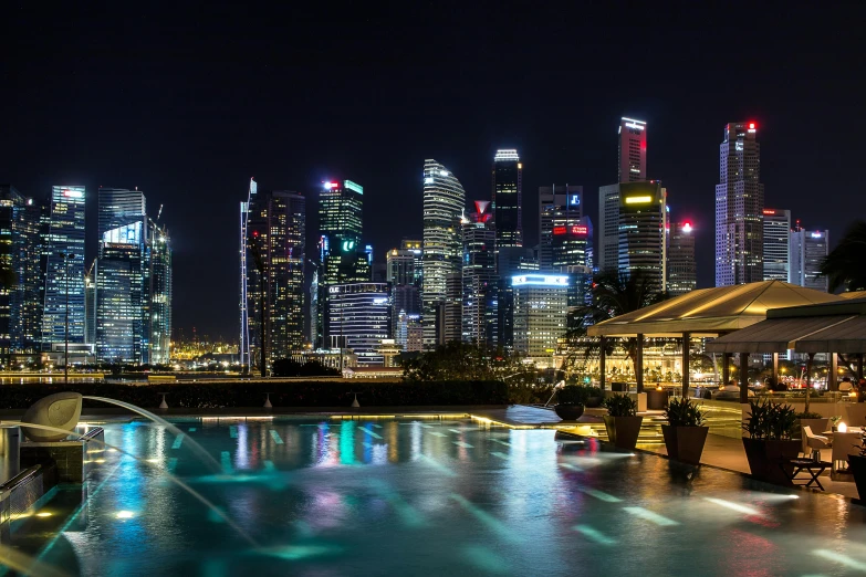 a pool in the middle of a city at night, by Patrick Ching, pexels contest winner, happening, the singapore skyline, foster and partners, al fresco, panoramic