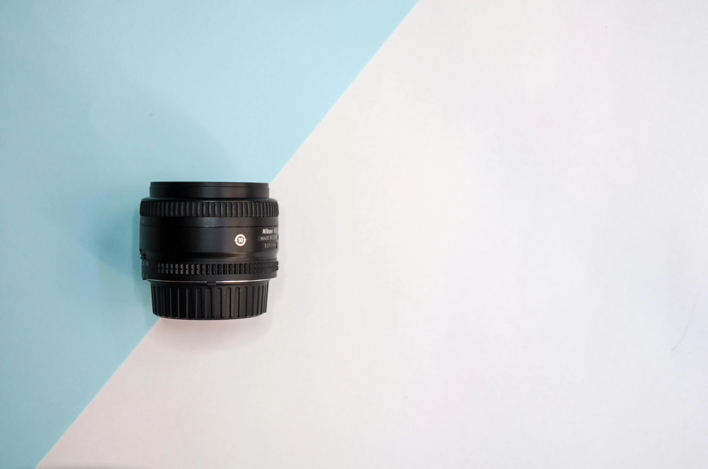 a camera lens on a blue and white background, by Adam Marczyński, unsplash, postminimalism, miniature product photo, sigma 2 4 mm, photo - realistic nikon 3 5 mm, on a pale background