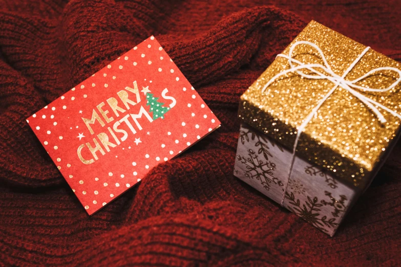 a couple of boxes sitting on top of a red blanket, pexels contest winner, merry, card, gold, medium close up