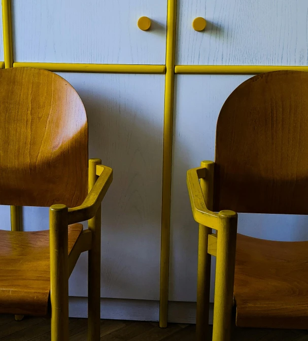 a couple of wooden chairs sitting next to each other, by Sven Erixson, unsplash, de stijl, cupboards, colors: yellow, close - up photograph, 4 k -