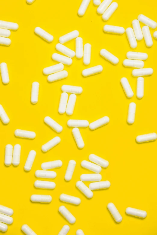 white pills scattered on a yellow background, unsplash, tubes, #trending, reddit post, sprinkles