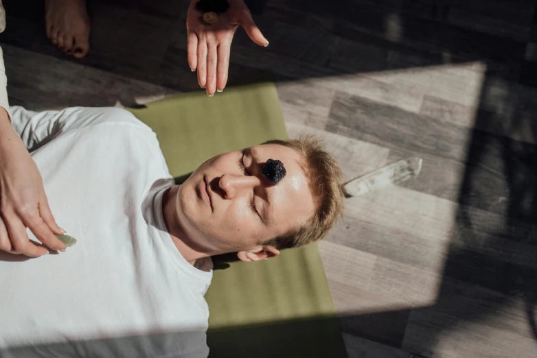 a man sitting on top of a yoga mat, trending on pexels, massurrealism, gemstone forehead, healing pods, person in foreground, lying dynamic pose