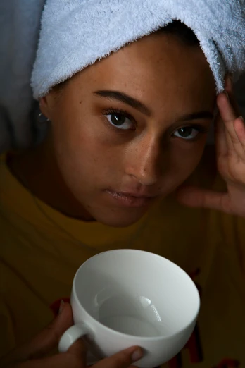 a woman with a towel on her head holding a cup, a portrait, inspired by Elsa Bleda, trending on pexels, mixed race woman, insomnia, dewy skin, breakfast