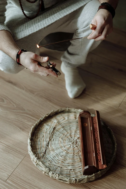 a person sitting on the floor cutting a piece of chocolate, by Jan Tengnagel, hurufiyya, incense, within radiate connection, holding the elder wand, wicker art