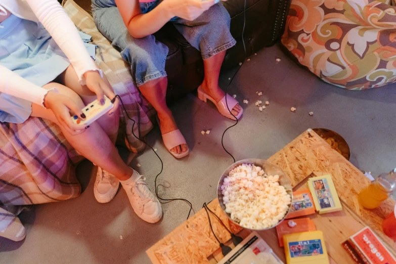 a group of people sitting on a couch playing a video game, by Everett Warner, trending on pexels, hyperrealism, tins of food on the floor, popcorn machine, summer setting, instagram story