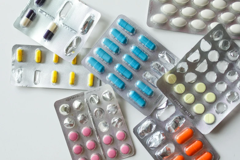 a bunch of pill packs sitting on top of a table, inspired by Damien Hirst, pexels, plasticien, on a white table, shields, close up, looking partly to the left