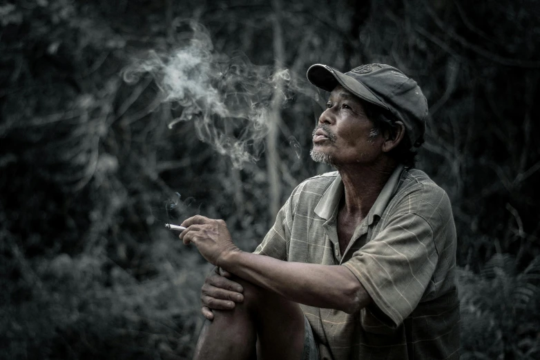 a man sitting on the ground smoking a cigarette, by Adam Marczyński, sumatraism, high quality image, hillbilly, thinker, unsplash photo contest winner