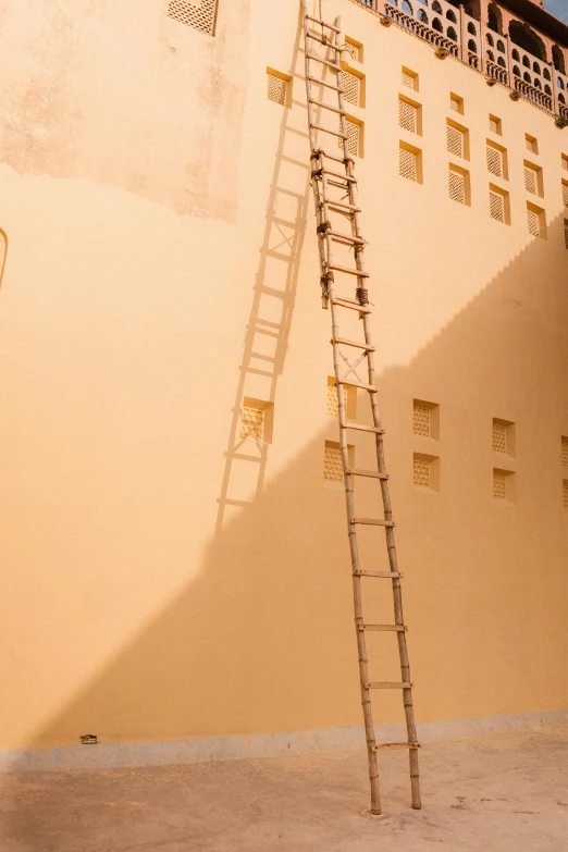 a ladder leaning against the side of a building, a photo, inspired by Ricardo Bofill, pexels contest winner, light and space, during sandstorm, light tan, climber, white wall