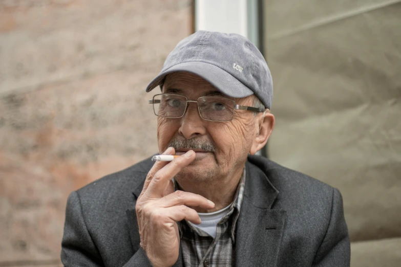 a man with glasses and a hat smoking a cigarette, photograph taken in 2 0 2 0, gordon murray, profile image, fan favorite