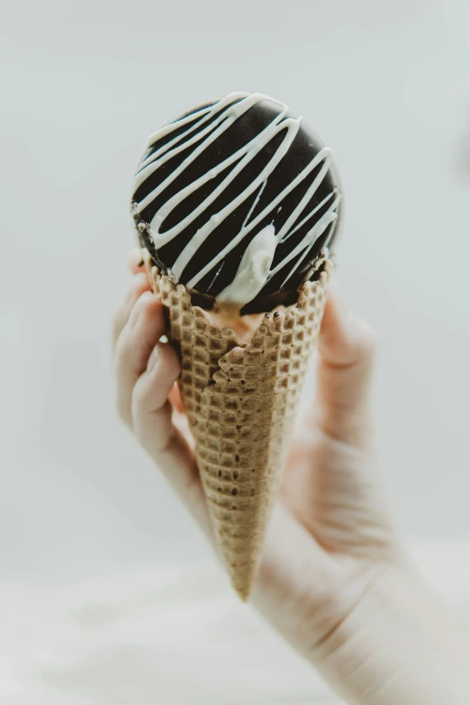 a person holding an ice cream cone in their hand, unsplash, black velvet, glaze, high angle close up shot, striped