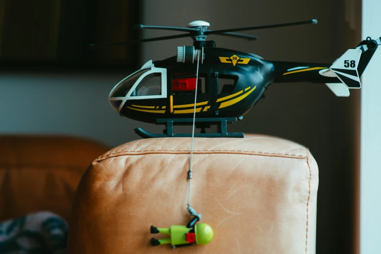 a toy helicopter sitting on top of a couch, by Romain brook, pexels contest winner, avatar image, emergency, black helicopters, tiny person watching