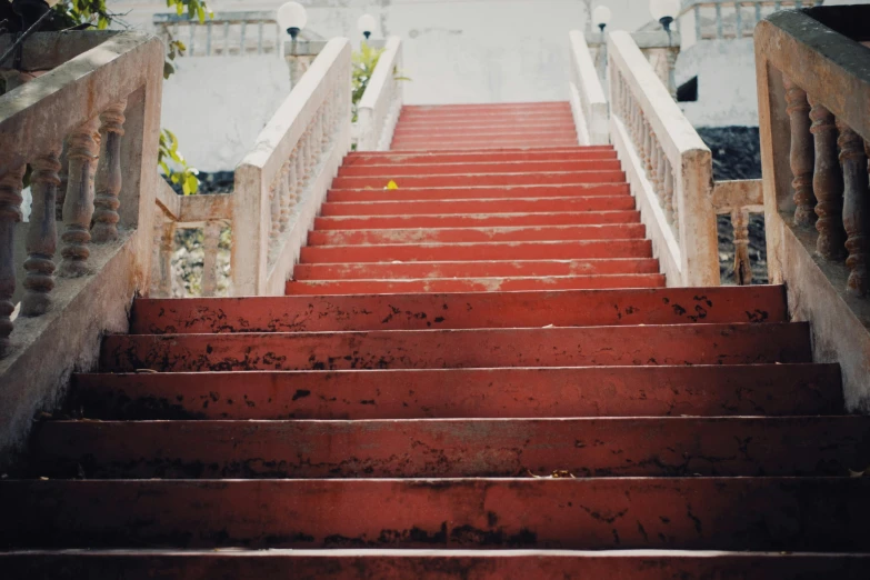 a set of red stairs leading up to a building, inspired by Elsa Bleda, unsplash, baroque, faded and dusty, assamese aesthetic, 2 0 0 0's photo, built on a steep hill