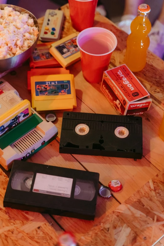 a table topped with a bowl of popcorn and a bowl of soda, an album cover, pexels, video art, vhs camcorder footage, board games on a table, college party, old tape