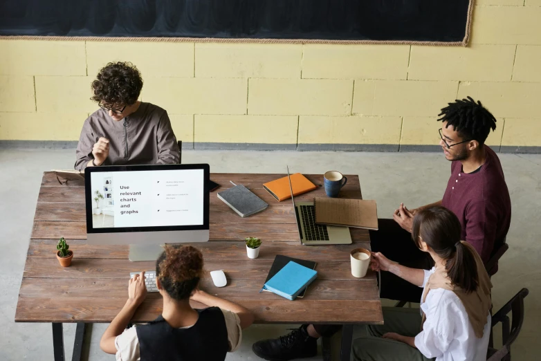 a group of people sitting around a wooden table, trending on unsplash, academic art, looking at monitor, teacher, product introduction photo