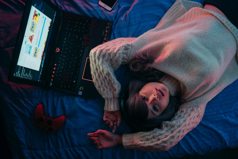 a woman laying on top of a bed next to a laptop computer, inspired by Elsa Bleda, trending on pexels, upside down stranger things, pc gaming, red and blue lighting, dafne keen