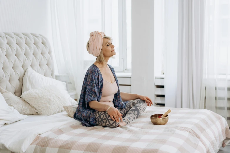 a woman sitting on a bed with a bowl of food, trending on pexels, arabesque, turban, meditation pose, anna nikonova aka newmilky, older woman