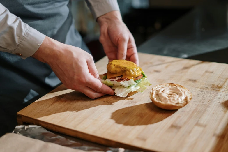 a person preparing a sandwich on a cutting board, by Joe Bowler, pexels contest winner, hamburger mix jellyfish, battered, thumbnail, plating