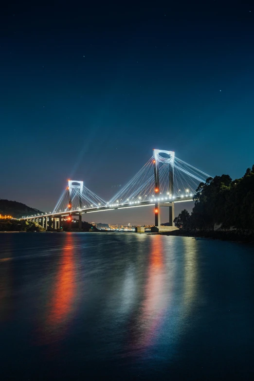 a bridge over a body of water at night, night-time, surrounding the city