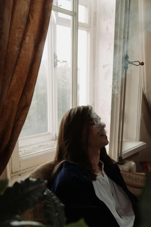 a woman sitting on a couch in front of a window, inspired by Nan Goldin, pexels contest winner, renaissance, smoke around him, low quality footage, in a castle, profile image