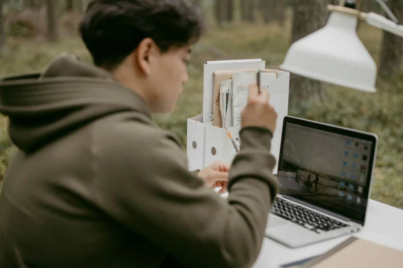 a man sitting in front of a laptop computer, by Emma Andijewska, pexels contest winner, forest picnic, asian male, inspect in inventory image, avatar image