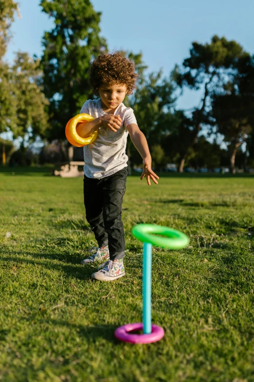 a little boy that is standing in the grass with a frisbee, of the game portal, multi - coloured, square, small