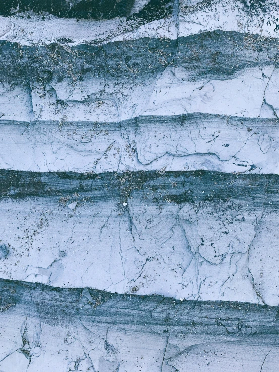 a man riding a snowboard on top of a snow covered slope, an album cover, inspired by Anselm Kiefer, trending on unsplash, concrete art, blue veins, geological strata, close-up print of fractured, concrete _ wall ) ]