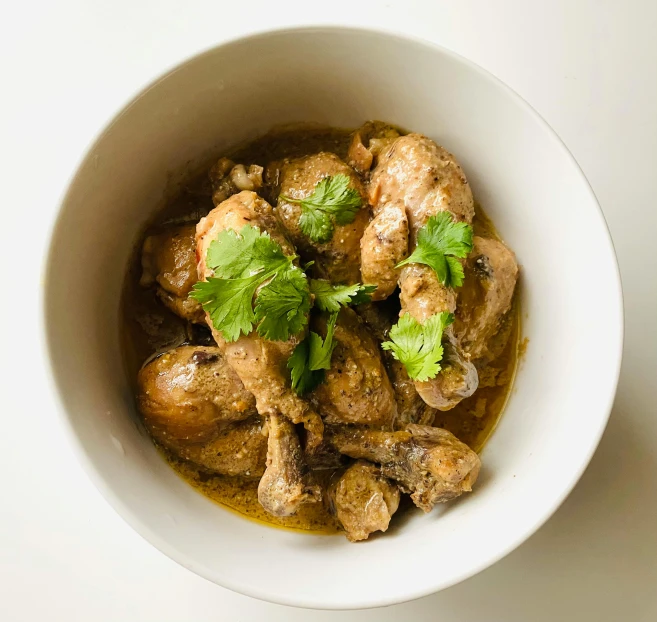 a close up of a bowl of food on a table, by Carey Morris, hurufiyya, chicken, high view, brown gravy, 王琛