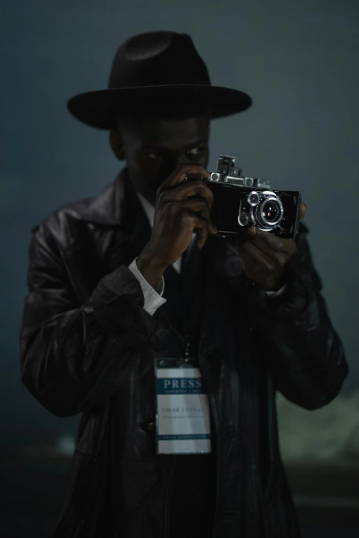 a man taking a picture with a camera, inspired by Gordon Parks, afrofuturism, black stetson and coat, adut akech, ( ( theatrical ) ), (night)