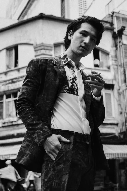 a black and white photo of a man standing in front of a building, an album cover, inspired by Gang Hui-an, unsplash, shin hanga, wearing a fancy jacket, with high cheekbones, paisley, smoking