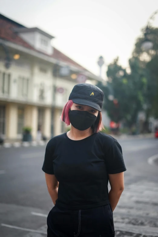 a woman standing in the middle of a street wearing a face mask, by Adam Rex, black cap, arsitektur nusantara, wearing black tshirt, federation clothing