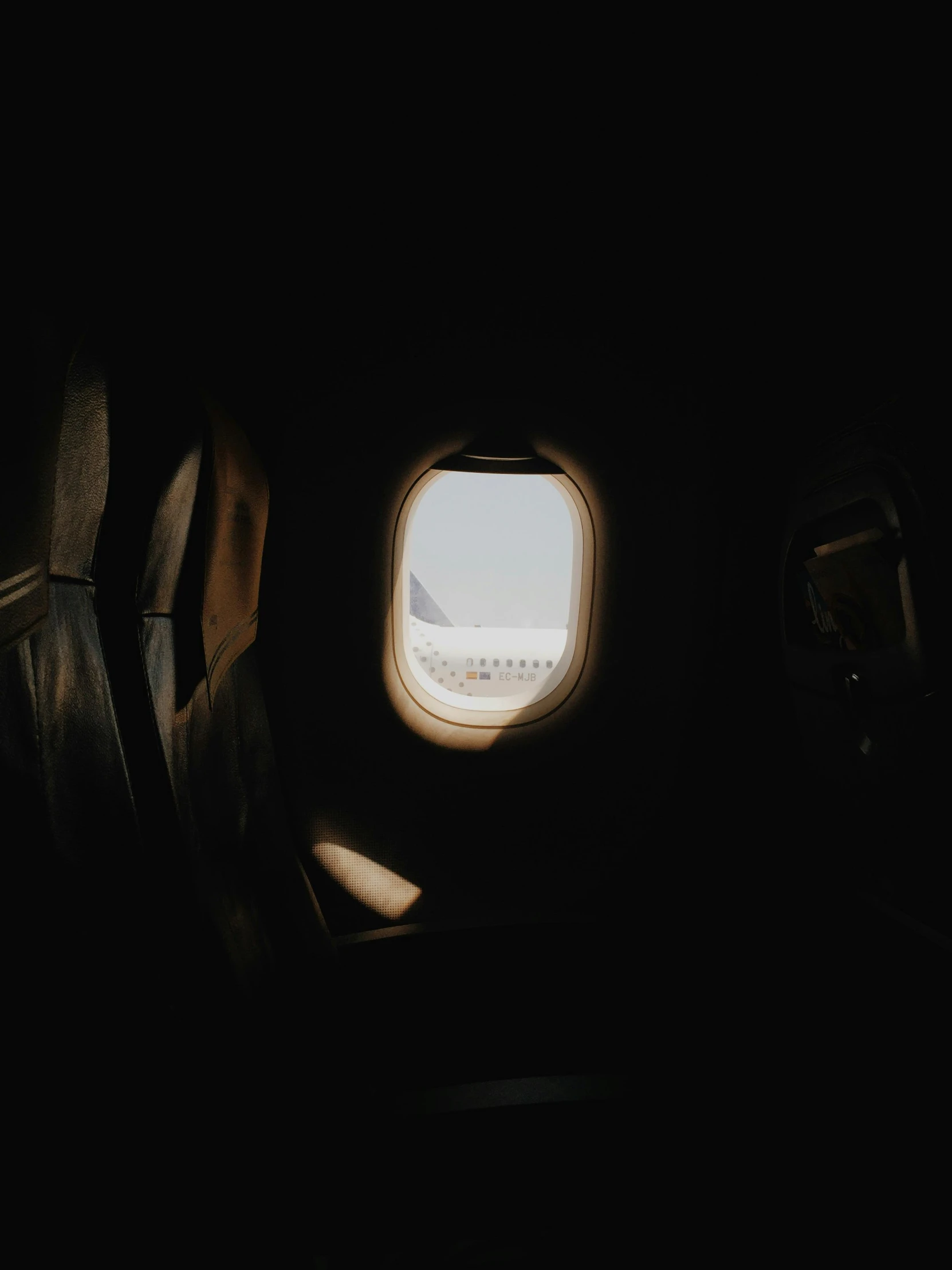 the inside of an airplane looking out the window, pexels contest winner, light and space, dark and beige atmosphere, looking through a portal, inside of a cabin, dark and dusty