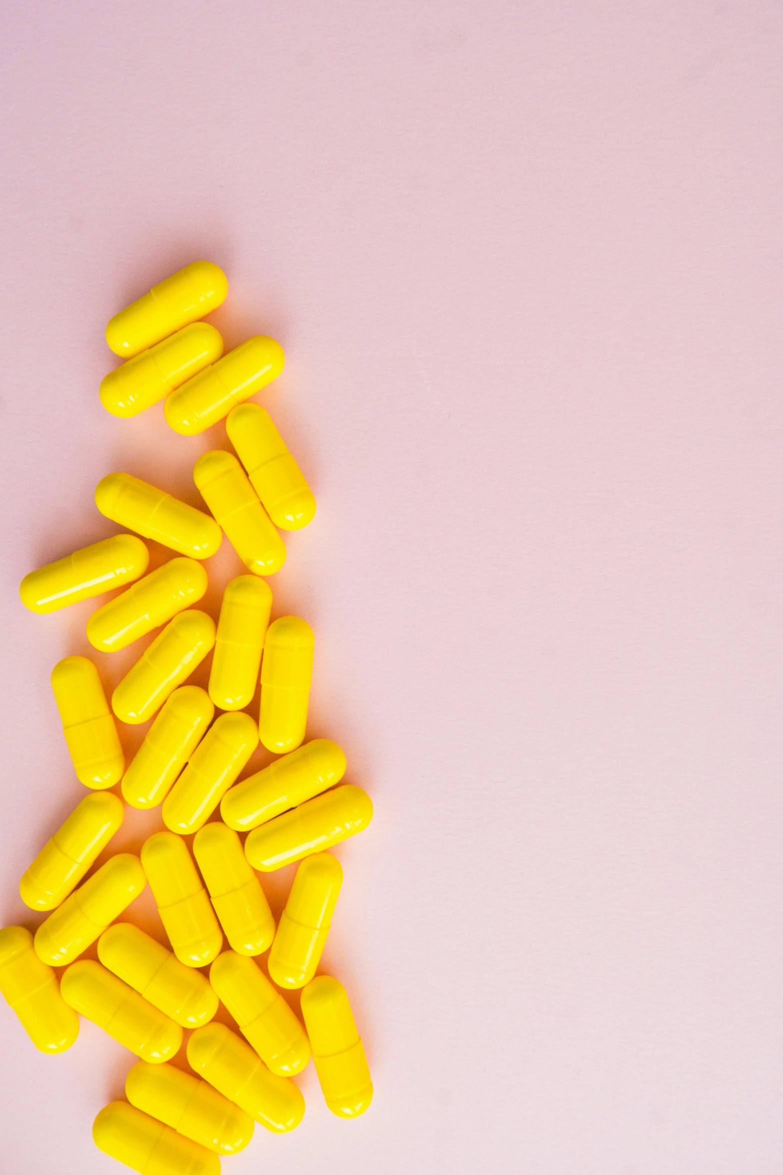 a pile of yellow pills on a pink background, by Nicolette Macnamara, pexels, antipodeans, multiple stories, on a gray background, emily rajtkowski, made of nanomaterials