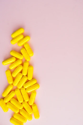 a pile of yellow pills on a pink background, by Nicolette Macnamara, pexels, antipodeans, multiple stories, on a gray background, emily rajtkowski, made of nanomaterials