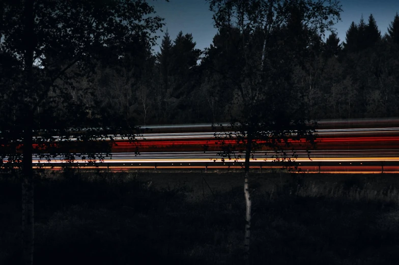a long exposure photo of a train passing through a forest, by Thomas Häfner, tail lights, busy night, screensaver, thin red lines