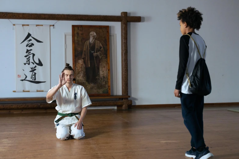 a woman sitting on the ground talking on a cell phone, inspired by Ma Quan, art & language, in a dojo, two still figures facing camera, ashteroth, wearing dark green robes