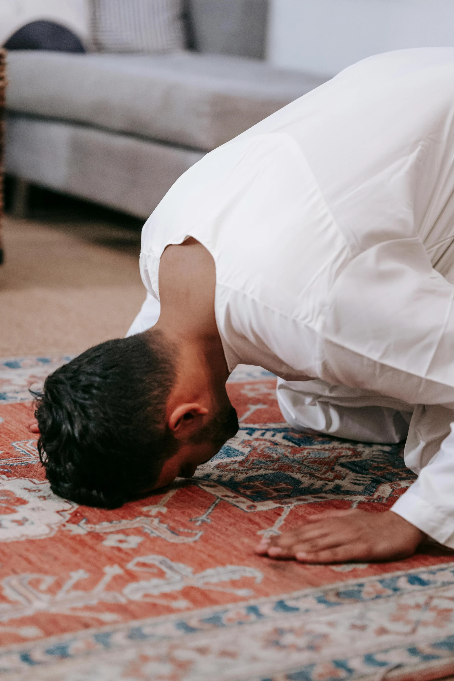 a man praying on a rug in a living room, by Carey Morris, pexels contest winner, hurufiyya, bent - over posture, neck up, groom, head tilted downward