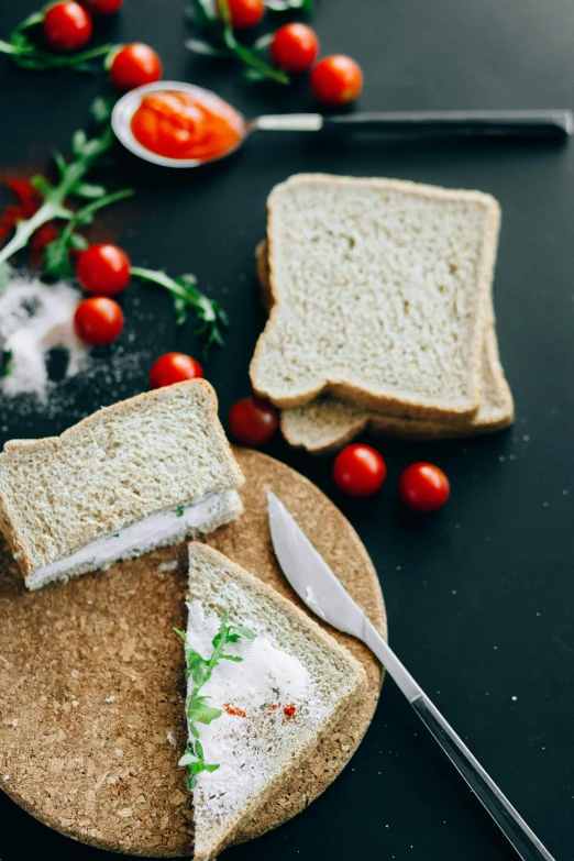 a sandwich cut in half sitting on top of a cutting board, by Andries Stock, unsplash, renaissance, brown bread with sliced salo, cream of the crop, light scatter, also one tomato slice