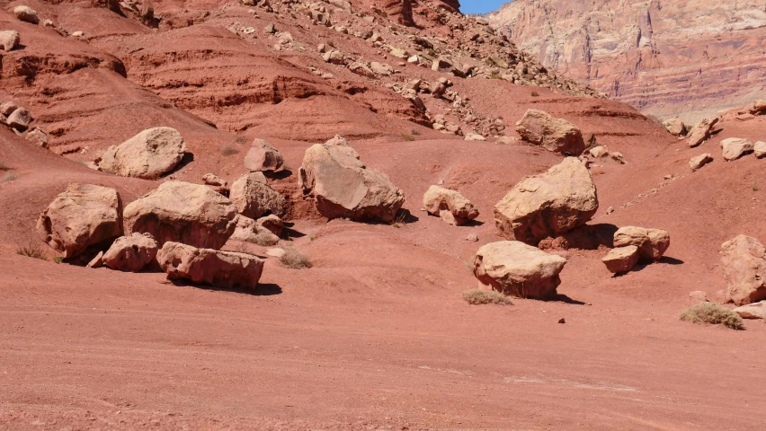 a person riding a horse through a desert, red sandstone natural sculptures, ((rocks)), gravel and scree ground, /r/earthporn