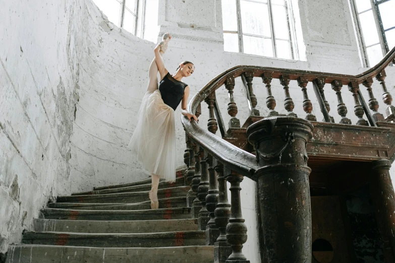 a woman that is standing on some stairs, by Elizabeth Polunin, pexels contest winner, arabesque, wearing a tutu, valentin serov style, performing, ad image