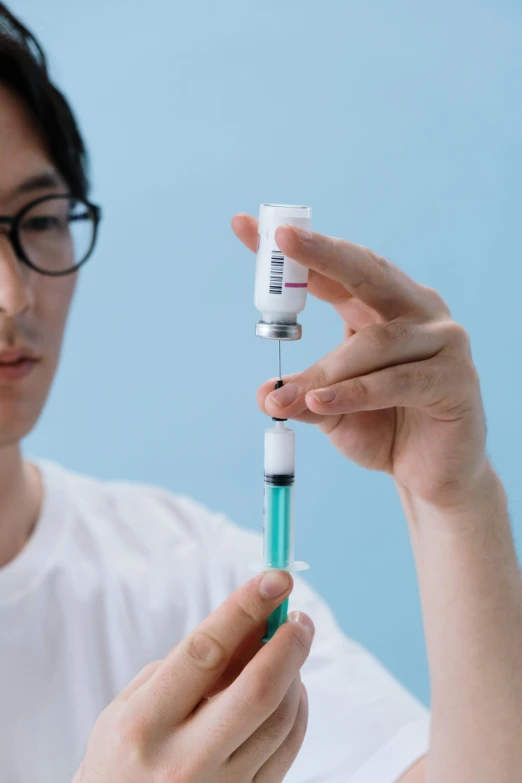 a close up of a person holding a syll, unsplash, holding syringe, asian male, educational, soft volume absorbation