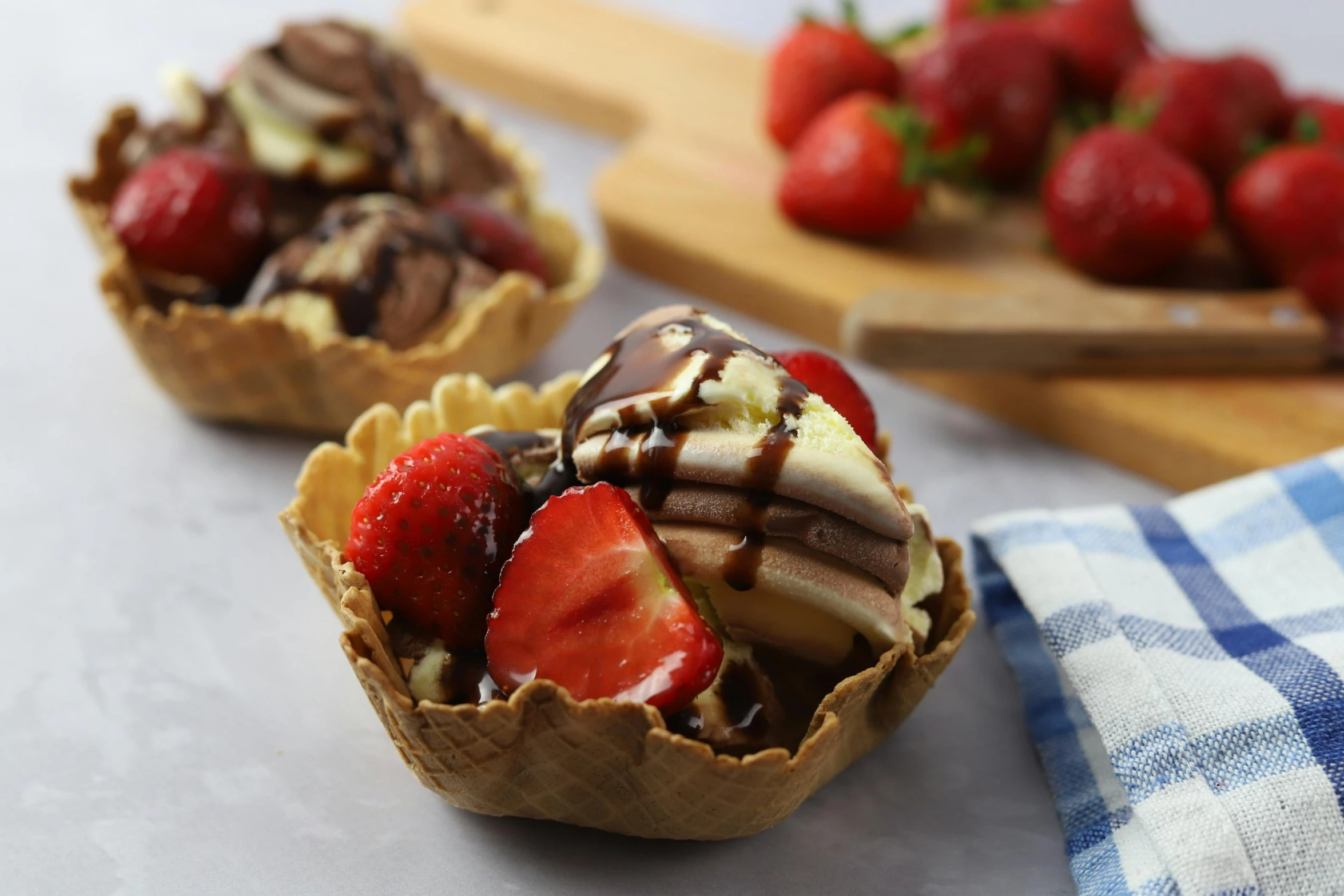 a couple of desserts sitting on top of a table, bowl filled with food, cone shaped, strawberries, brown