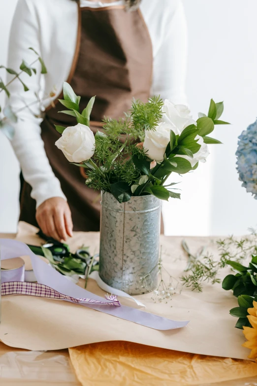 a woman arranging flowers in a vase on a table, featured on pinterest, blue and grey theme, commercially ready, carefully crafted, on center