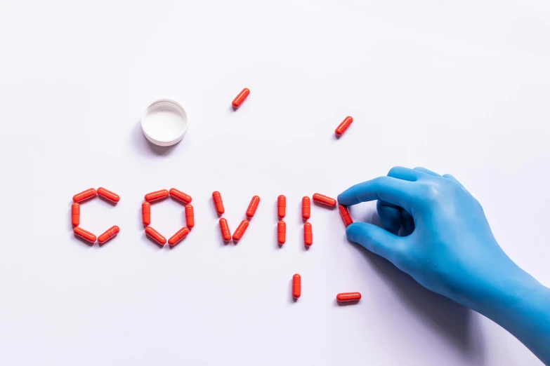 a person in a blue glove writing the word covid, by Matt Cavotta, trending on pexels, pills, red writing, beauty is a virus, colourised