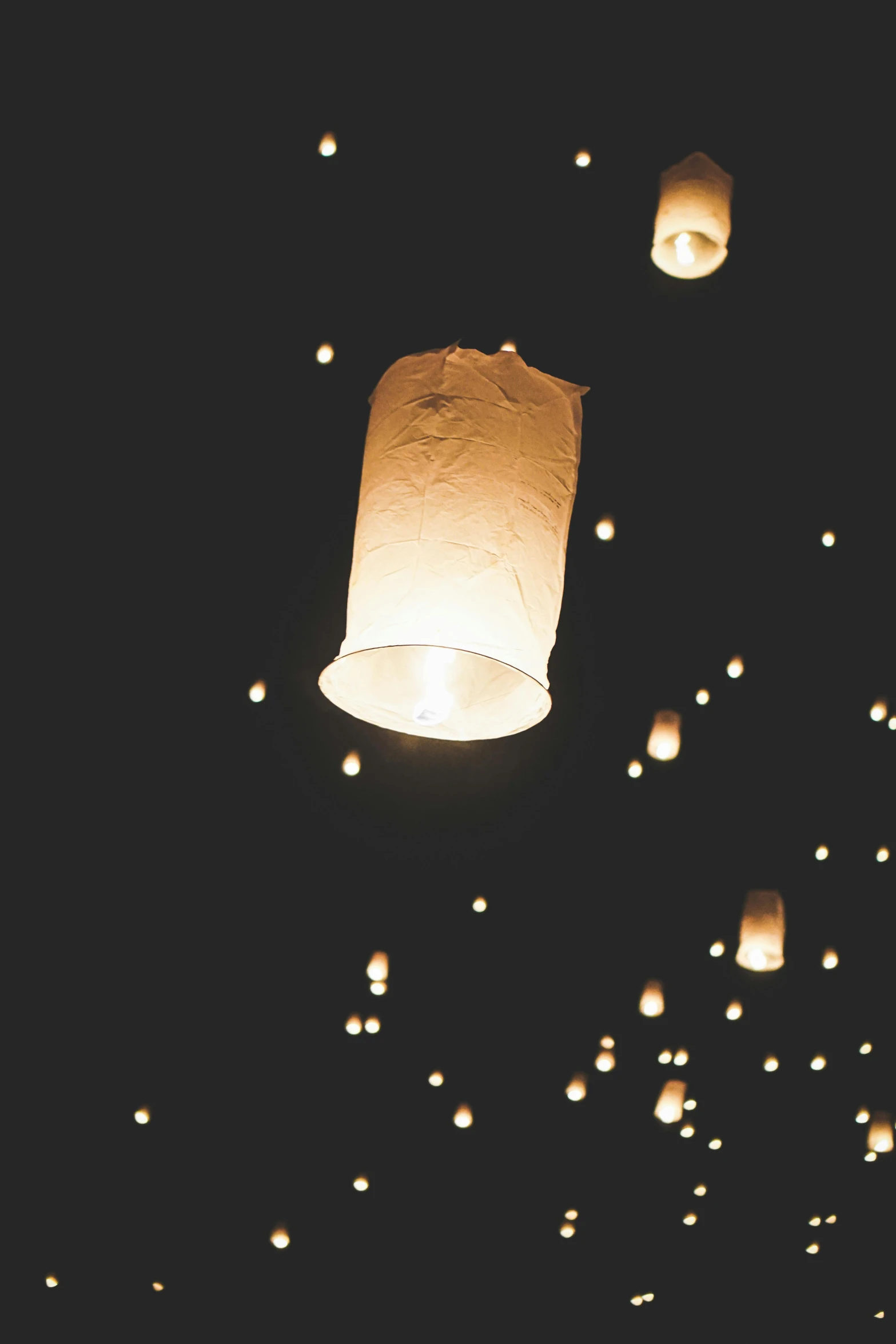 a group of people flying paper lanterns in the air, an album cover, by Dan Scott, unsplash, light and space, 2000s photo, low detail, at nighttime, insandely detailed