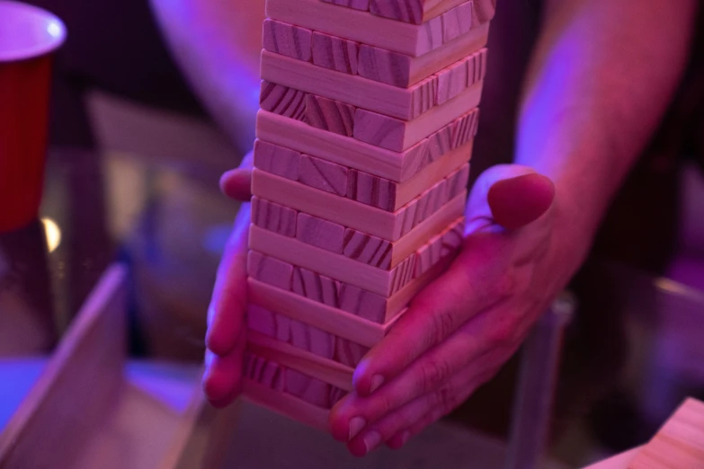 a close up of a person holding a stack of cards, by Lee Loughridge, unsplash, process art, pink lighting, wooden structures, games, block party