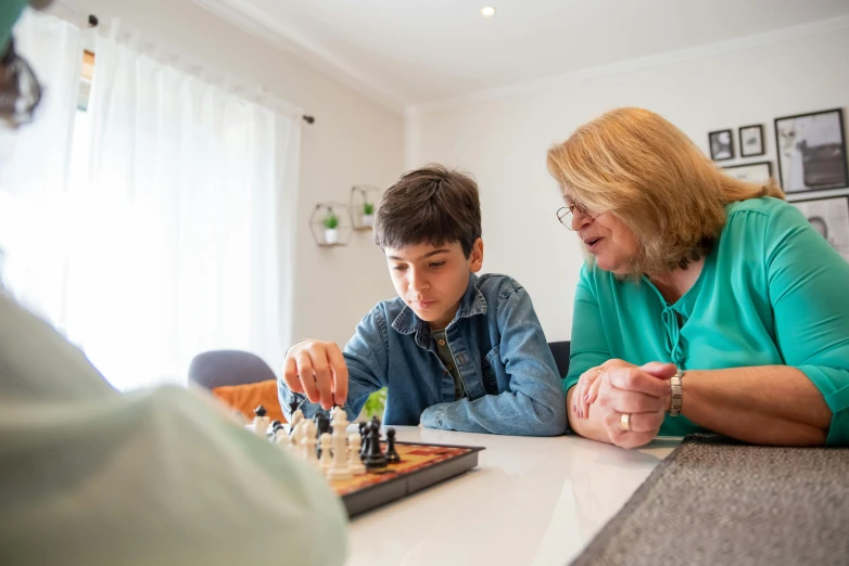 a woman and a boy playing a game of chess, by Lisa Milroy, pexels contest winner, te pae, at home, profile image, person in foreground