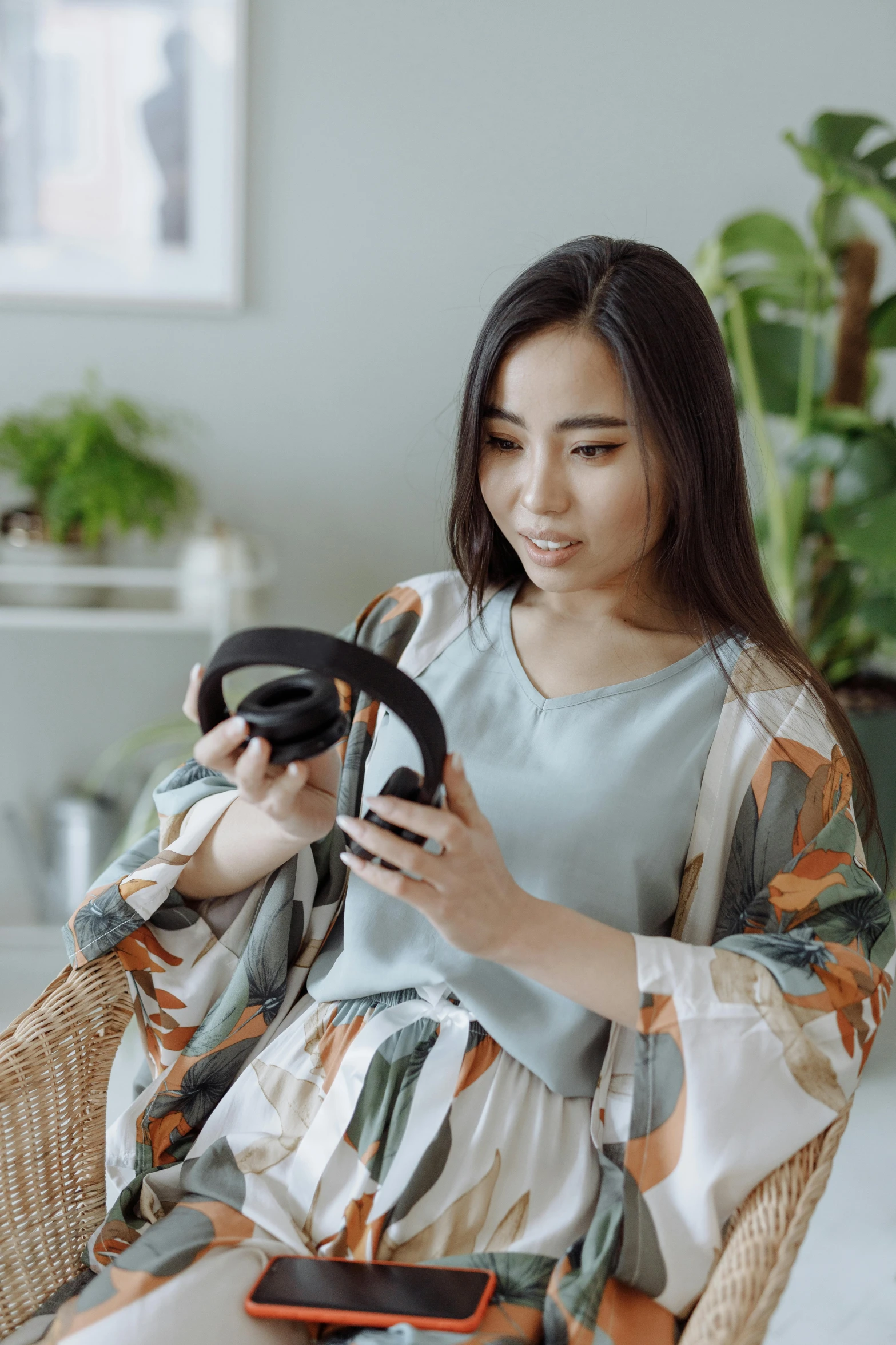 a woman sitting in a chair using a cell phone, wearing black headphones, asian hyperdetailed, designer product, wireless headphone stand