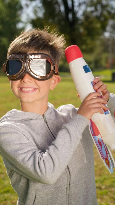 a young boy wearing goggles holding a toy rocket, inspired by Jean Tabaud, shutterstock, portrait mode photo, top gun, thumbnail, game ready