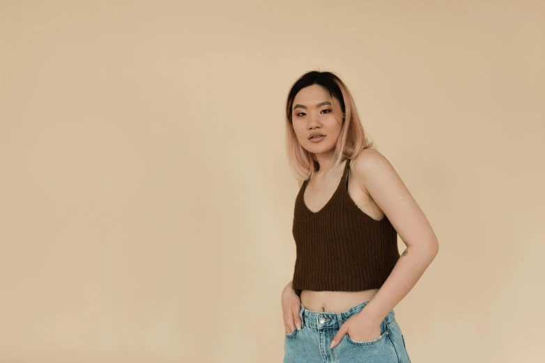 a woman standing with her hands in her pockets, inspired by helen huang, trending on pexels, realism, wearing tank top, brown:-2, nonbinary model, gongbi