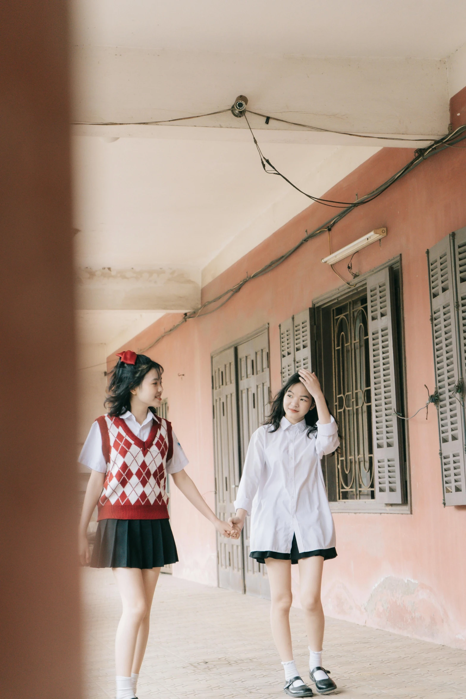 a couple of girls standing next to each other, by Tan Ting-pho, trending on unsplash, realism, dressed as schoolgirl, couple walking hand in hand, ( ( theatrical ) ), dang my linh